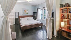 A bedroom with a wooden bed, white curtains, a bookshelf, and a painting on the wall. - Clean & Spacious-Walk to the Fairmont, great restaurants, coffee shops and wine (Sonoma)