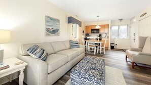 Una sala de estar acogedora con un sofá, un tapete estampado y una zona de comedor con una mesa y sillas.