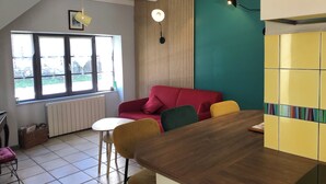 A modern kitchen with a wooden countertop, a red sofa, and a dining area with yellow chairs. - House made of regional stones, typical from Auvergne, greenery landscape (Gouttières)