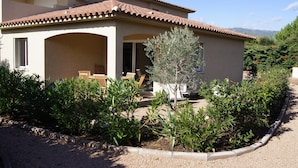 A two-story building with a covered patio area, outdoor seating, and a garden with various plants. - Modern mini villa T3 800 m from the beach - all comforts, air conditioning, terrace (Lecci)