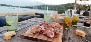 Un tavolo con bevande, un tagliere con salumi e un cesto di vimini.