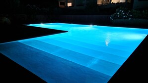 A swimming pool with a clear blue water feature and a dark surrounding area. - Modern mini villa T3 800 m from the beach - all comforts, air conditioning, terrace (Lecci)