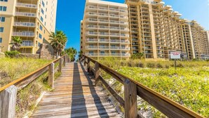 A wooden boardwalk leading to a beachfront hotel with multiple balconies and a sign indicating a dune area. - Perfect Family or Romantic Getaway~Best View in Orange Beach~Summer specials (Orange Beach)