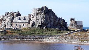 Una casa de piedra con una gran formación rocosa al frente.