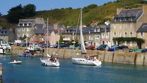 Un puerto con barcos amarrados, un muelle de piedra y edificios con tejados de pizarra.