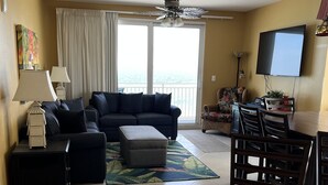 A living room with a sofa, ottoman, and a dining area with chairs and a table.