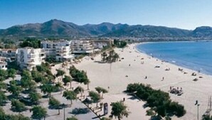 A coastal beach with buildings and mountains in the background. - Panoramic view of the Mediterrannée, apartment on canal near beach  (Rosas)