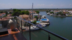 A marina with boats docked, a swimming pool, and residential buildings in the background. - Panoramic view of the Mediterrannée, apartment on canal near beach  (Rosas)