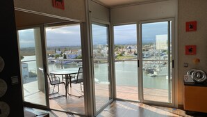 A modern room with a glass door leading to a balcony overlooking a marina and town. - Panoramic view of the Mediterrannée, apartment on canal near beach  (Rosas)