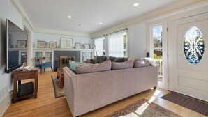 A spacious living room with a large sofa, a flat-screen TV, and a fireplace. - “Blue Door Cottage by the Sea,” La Jolla Village & Cove, Only 4 blocks to Beach  (La Jolla)