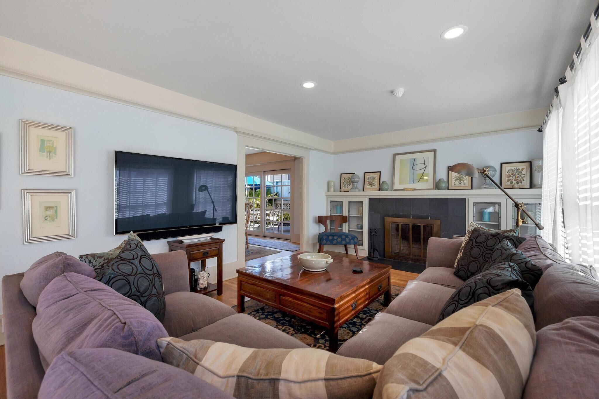 A living room with a large flat-screen TV, a fireplace, and a sofa set.