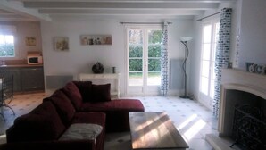 Ein Wohnzimmer mit einer Couch, einem Couchtisch, einem Kamin und einer Küche im Hintergrund.