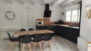 Eine moderne Küche mit einem Holztisch, schwarzen Stühlen, einer Mikrowelle und einer schwarzen Dunstabzugshaube.