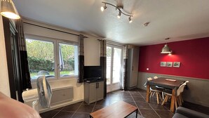 Une cuisine moderne avec un coin repas, de grandes fenêtres et un mur d’accent rouge.