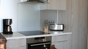 Una cocina compacta con horno integrado, cafetera y tostadora sobre la encimera.
