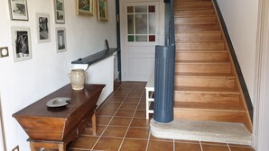 Una escalera con peldaños de madera y barandilla negra, que conduce a una puerta blanca con paneles de vidrio.