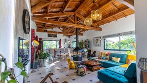 Amplia sala de estar con techo de madera alto, un sofá azul y una chimenea.