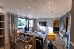 Een kamer met een wieg, een bed, een televisie, een bureau en een spiegel.