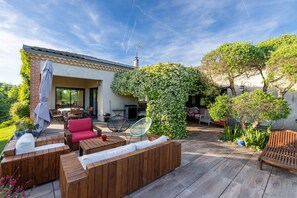 A patio with wooden furniture, a covered seating area, and a large tree. - Villa Magarre - Heated pool - Spa - Nature (Castelnau-de-Montmiral)