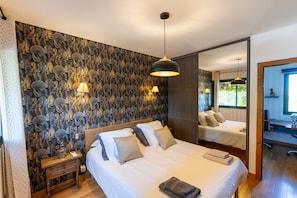 A bedroom with a large bed, bedside lamps, a mirror, and a wooden nightstand. - Villa Magarre - Heated pool - Spa - Nature (Castelnau-de-Montmiral)