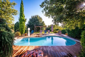 A wooden deck surrounding a swimming pool with lounge chairs and a pergola. - Villa Magarre - Heated pool - Spa - Nature (Castelnau-de-Montmiral)