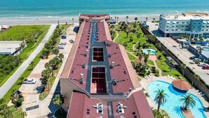 Un hotel con piscina en la azotea, estacionamiento y vista al océano.