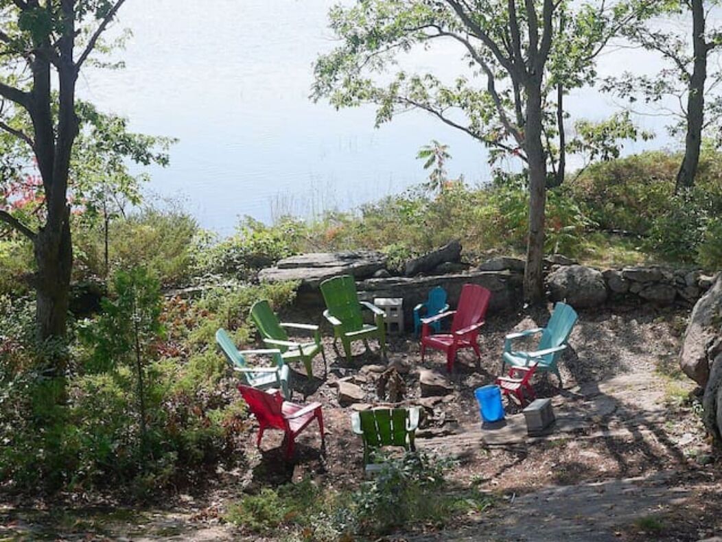 A campsite with outdoor seating and a view of a body of water.