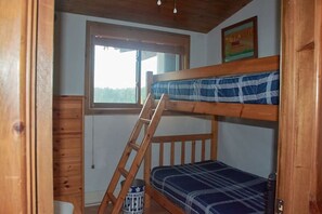 A bunk bed room with a ladder, a window, and a maple syrup can.
