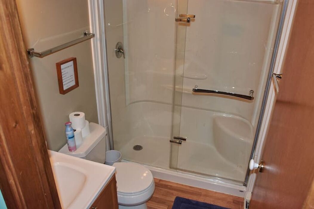 A bathroom with a glass-enclosed shower, a toilet, and a sink.