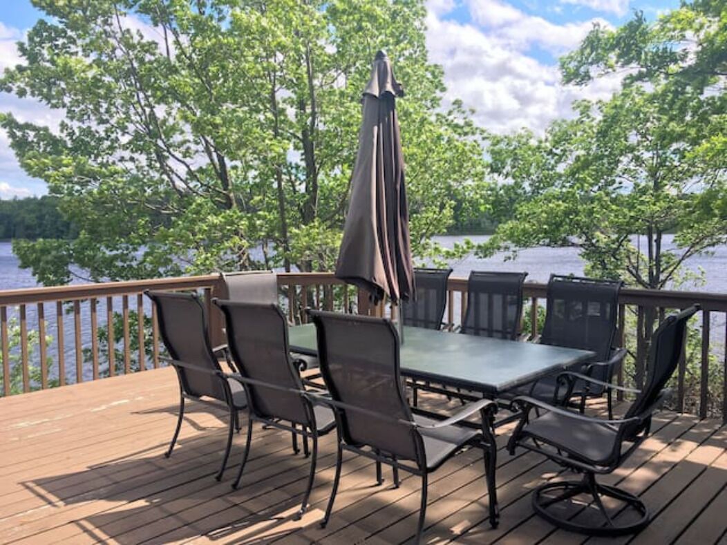 Une terrasse avec une table et des chaises, donnant sur un plan d’eau.