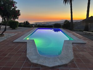 Une piscine offrant une vue sur le coucher du soleil et le paysage urbain lointain.