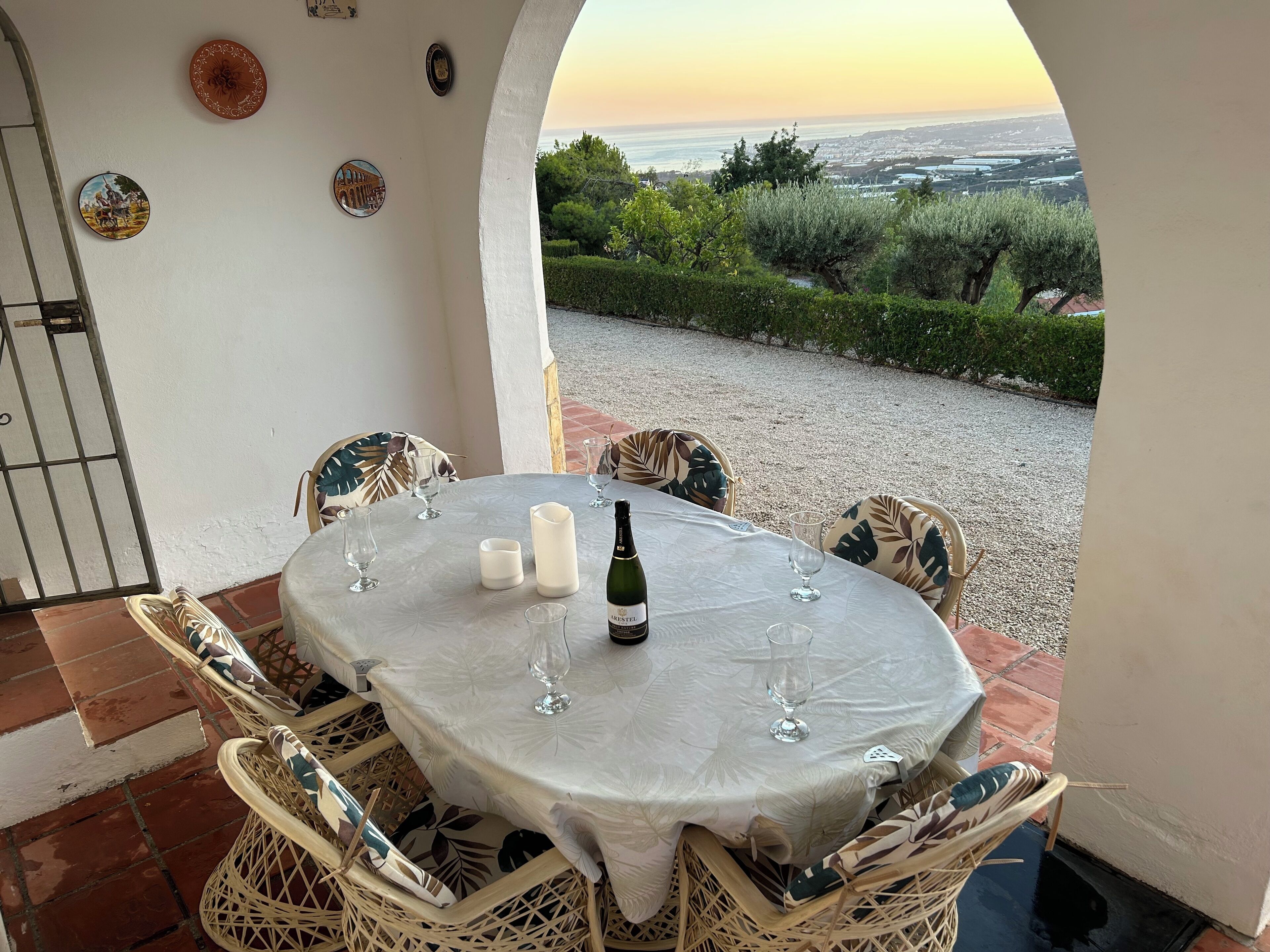 Une table dressée pour deux personnes, avec une bouteille de vin, des verres et une assiette décorative posée sur une nappe blanche.