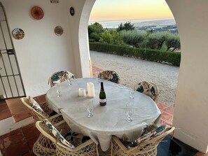 Une table dressée pour deux personnes, avec une bouteille de vin, des verres et une assiette décorative posée sur une nappe blanche.