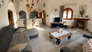 A spacious living room with a sofa, a coffee table, and a television. There is a kitchen area with cabinets and a dining table. - Independent villa, magnificent sea view, private swimming pool, WIFI (ALGARROBO)
