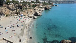 A coastal beach with clear blue waters, rocky cliffs, and a town in the background. - Independent villa, magnificent sea view, private swimming pool, WIFI (ALGARROBO)