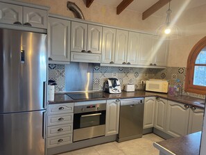 Une cuisine moderne dotée d’appareils électroménagers en acier inoxydable, de meubles blancs et de carreaux décoratifs sur le mur derrière l’évier ou la cuisinière.