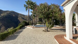 A gravel pathway leading to a white building with arches, surrounded by palm trees and a view of a hilly landscape. - Independent villa, magnificent sea view, private swimming pool, WIFI (ALGARROBO)