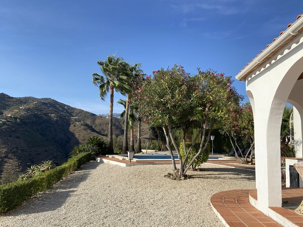 A gravel pathway leading to a white building with arches, surrounded by palm trees and a view of a hilly landscape. - Independent villa, magnificent sea view, private swimming pool, WIFI (ALGARROBO)
