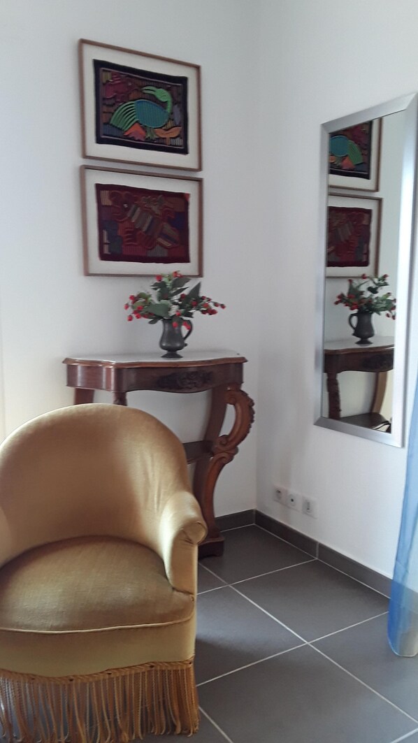 Una habitació amb un butac armchair de cuir, una taula auxiliar de fusta amb un ram de flors i tres quadres al mur.