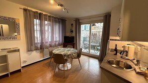 Un espacio habitable compacto con comedor, kitchenette y balcón con vistas.