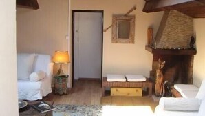 Ein gemütliches Zimmer mit einem Bett, einem kleinen Tisch mit Lampe, einem Kamin und einem gerahmten Bild an der Wand.