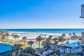 A resort with a pool, beach access, and palm trees.