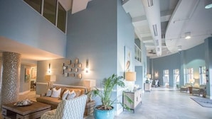 A spacious living area with a large sofa, a coffee table, and a potted plant. There is a staircase leading to an upper level. - 2BR Renovated Beachfront at Pelican, Stunning Ocean View, Pools Beach Chairs (Destin)