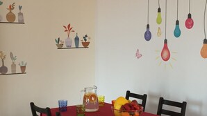 A dining area with a red tablecloth, chairs, a pitcher, glasses, and a bowl of fruit. - Cefalù Appart 4 (Cefalù)
