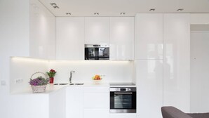 A modern kitchen with white cabinetry, a built-in oven, and a stainless steel range hood.
