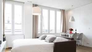 A modern hotel room with a large bed, a desk, and a chair.