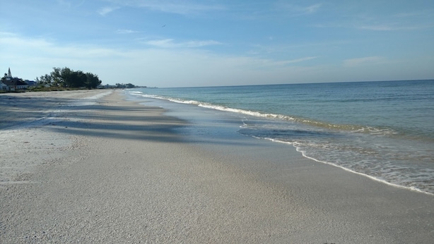 Une plage dotée d’un large rivage sablonneux et de vagues douces.
