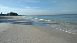 Ein Strand mit weitem Sandstrand und sanften Wellen.