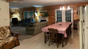 Ein Ferienhausinnenraum mit Esstisch, Stühlen, einer Couch und einem Kamin.