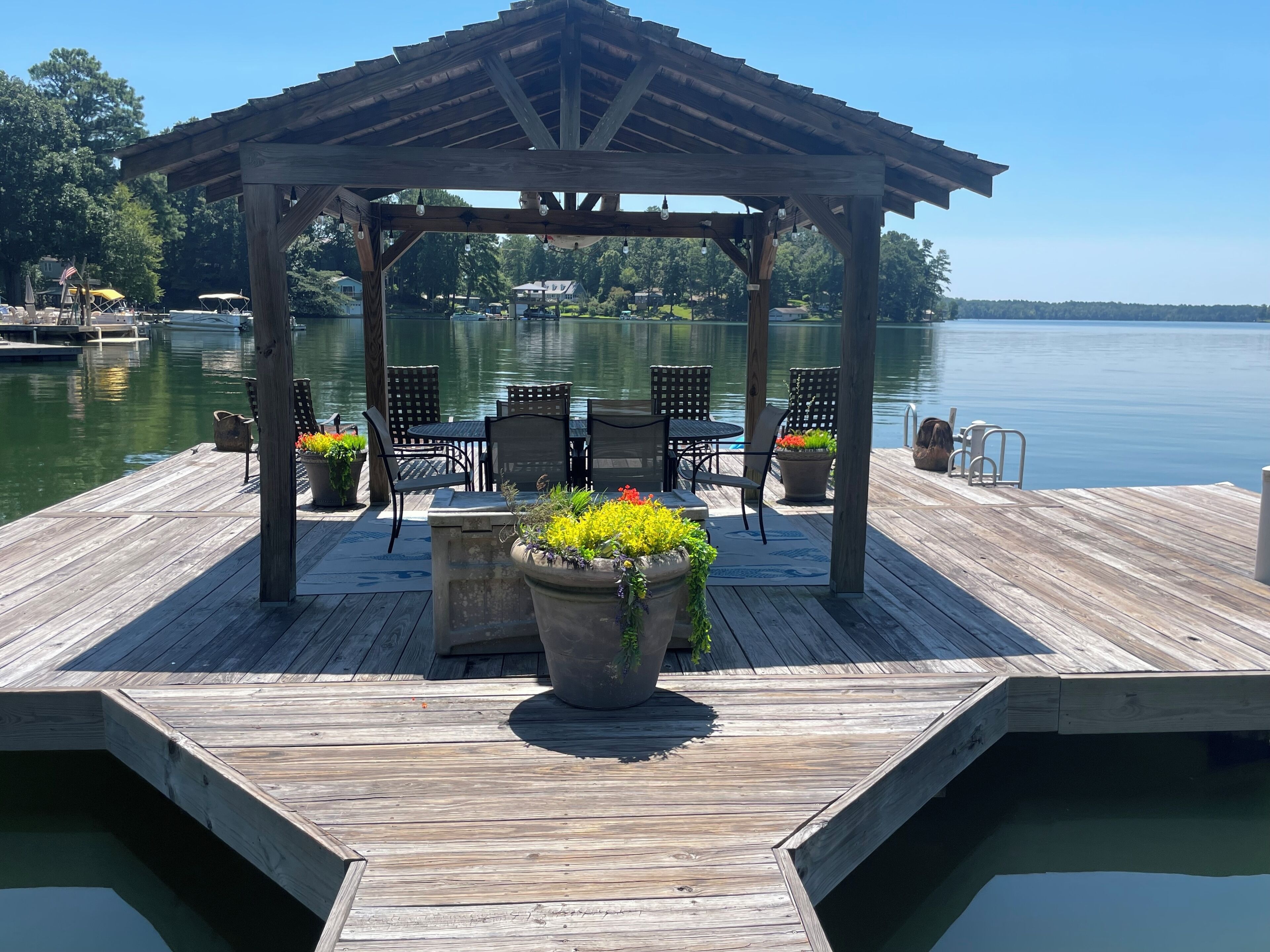 Un kiosque en bois, avec des chaises et des tables, situé sur une jetée au bord d’un lac.